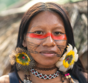 mulher indígena com brincos de pena e pintura tradicional vermelha e preta no rosto