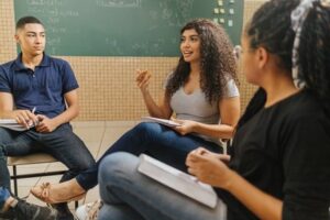 Alunos reunidos em sala de aula, sentados em círculo, indicando roca de ideias sobre a aula.