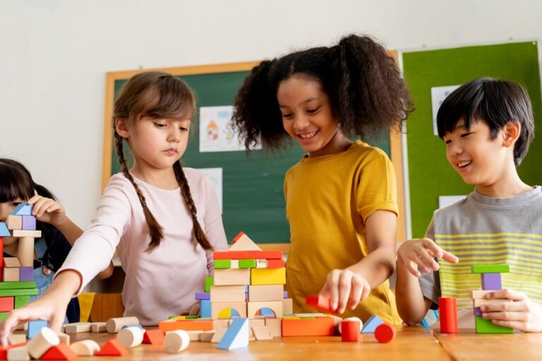 Crianças em uma sala de aula, de pé, brincando com peças de montar.