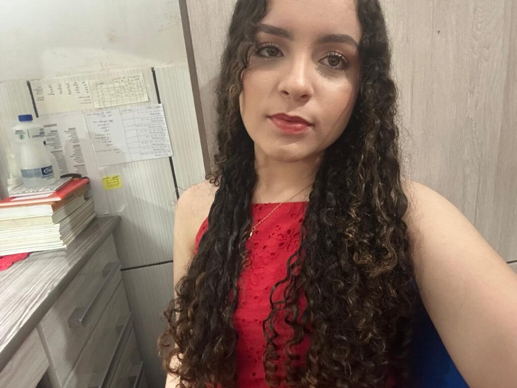 Maria Paula, estudante, em uma sala posando para a foto.