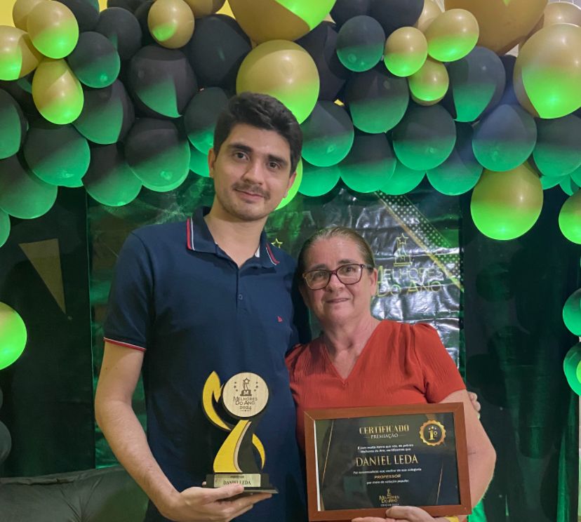 Daniel ao lado da mãe com um prêmio pelo seu trabalho.